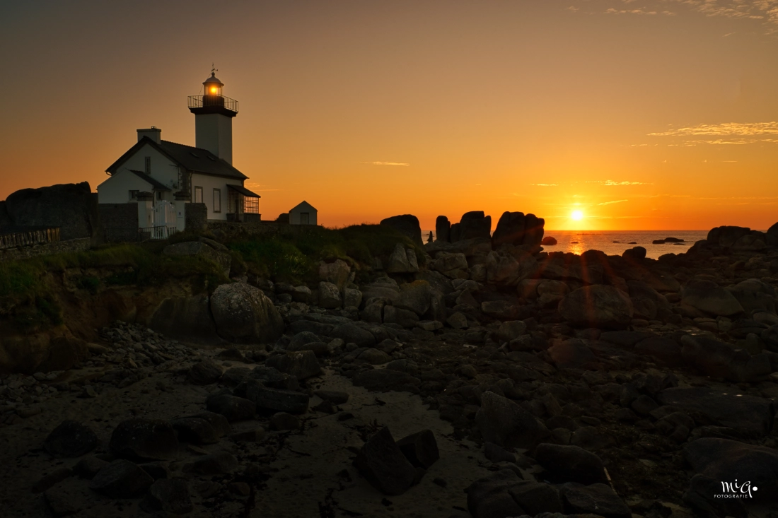 Leuchtturm Pontusval bei Brignogan-Plages in der Bretagne im warmen Licht des Sonnenuntergangs, umgeben von Granitfelsen an der atlantischen Küste