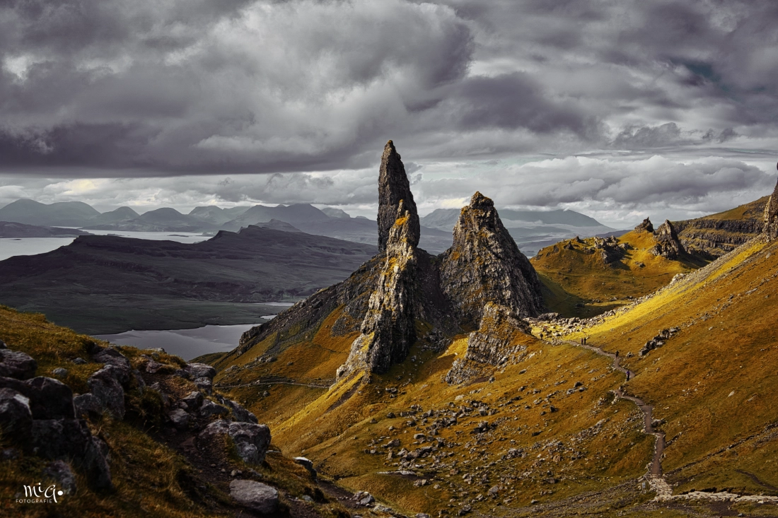 Der alte Mann des Nordens Die markanten Felsnadeln des Old Man of Storr auf der Isle of Skye unter dramatischem Wolkenhimmel mit goldenem Moosbewuchs und weitem Blick über die schottischen Highlands