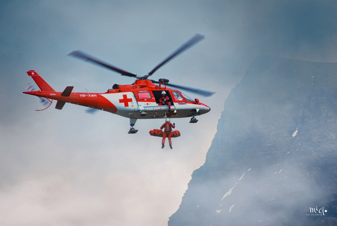 Rega Rettungshelikopter Agusta bei einer Rettungsdemonstration am Fliegerschiessen Axalp 2007 vor Bergkulisse