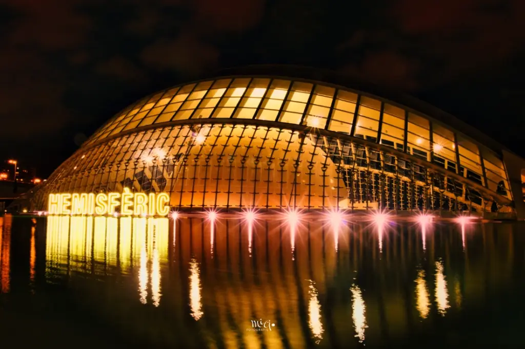 Das beleuchtete L'Hemisfèric in Valencia bei Nacht mit klarer Spiegelung im Wasserbecken