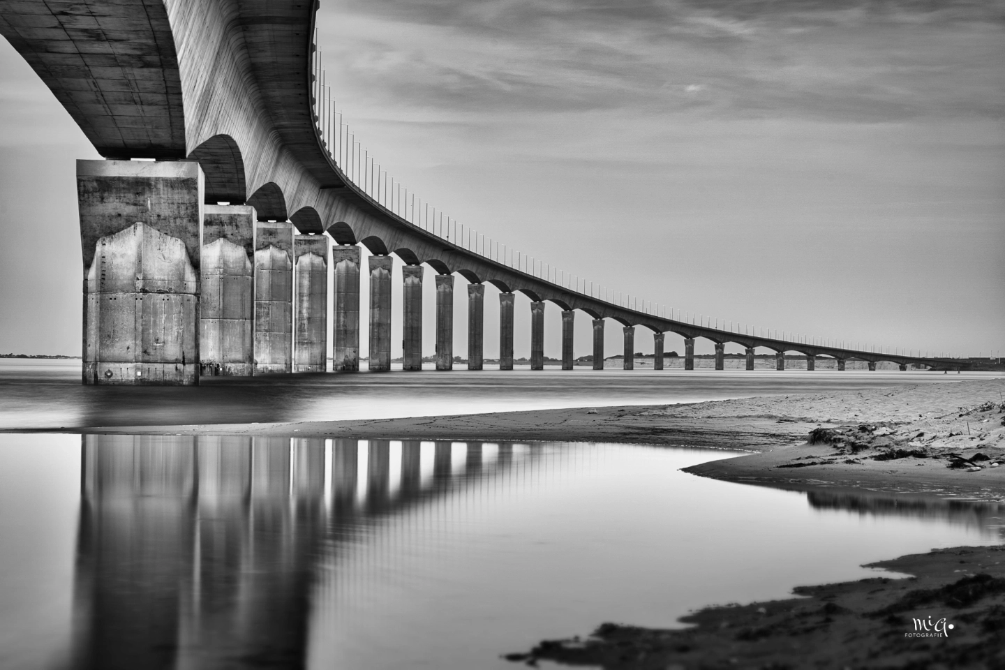 Bruecke Ile de Re Frankreich Schwarz-Weiss Architekturfotografie Schwarz-Weiss-Fotografie der Brücke zur Ile de Re (Pont de l'ile de Re) in Frankreich. Architekturaufnahme mit Fokus auf die Betonpfeiler, die sich im glatten Wasser spiegeln, unter einem leicht bewölkten Himmel.