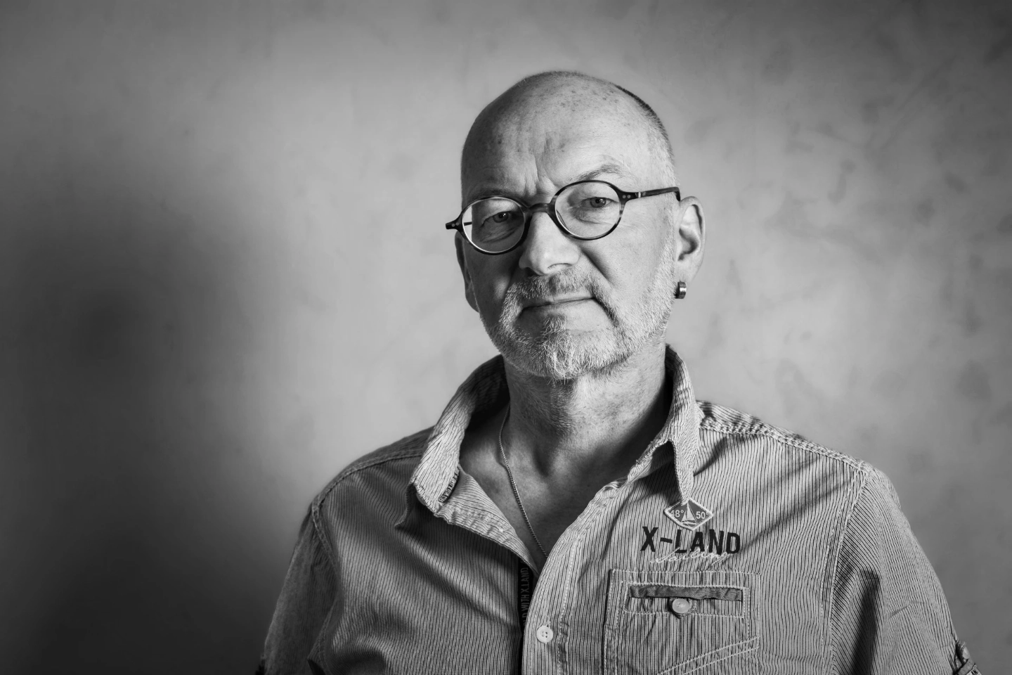 Michel Godart godart-foto Portraet Ueber-mich Nahaufnahme-Porträt in Schwarz-Weiss von Michel Godart (Godart-Foto.ch), Fotograf mit Brille und Bart, vor strukturiertem Hintergrund. Titelbild für die Über-mich-Seite.